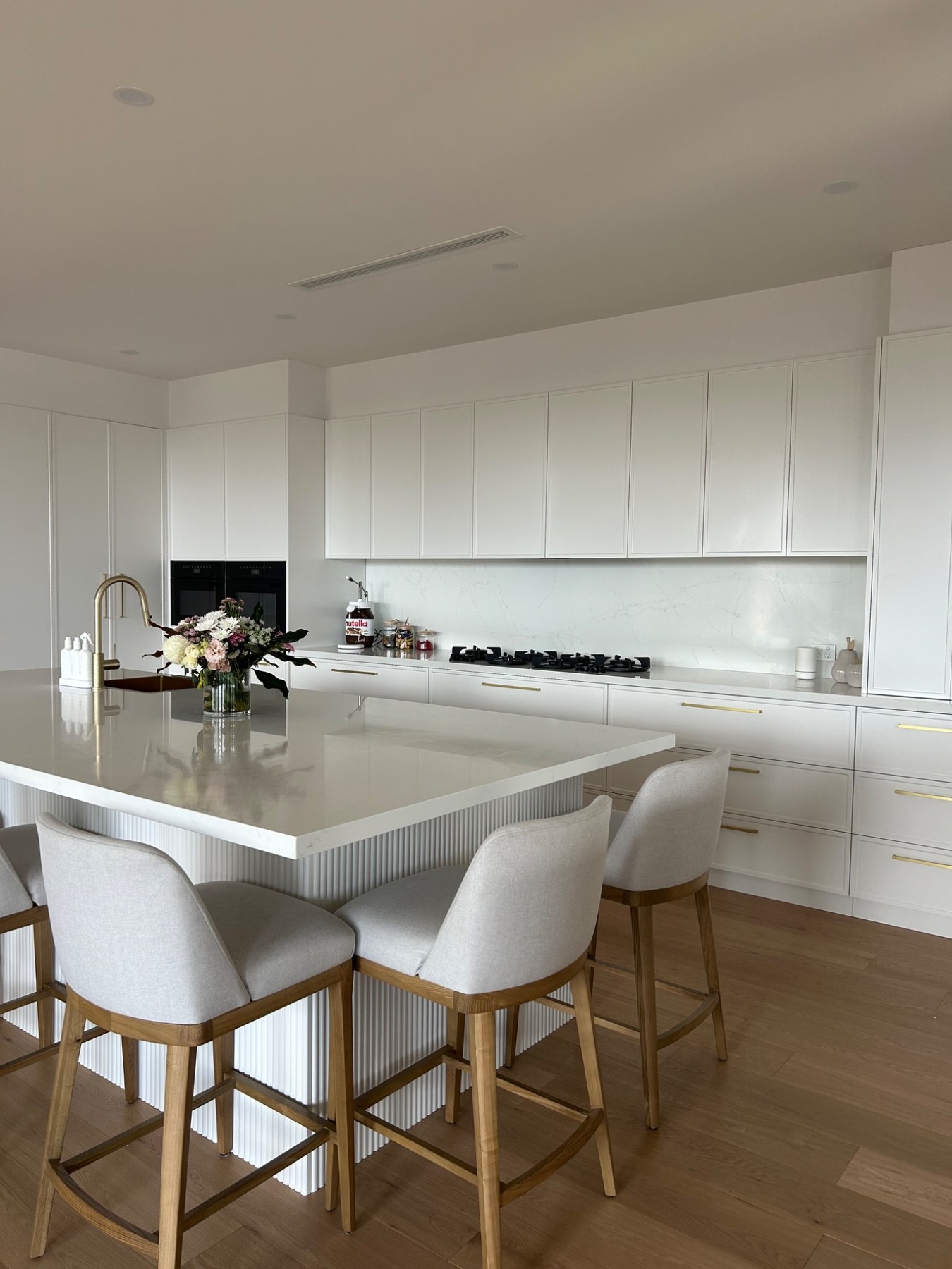 Contemporary white kitchen with stone island and brass fittings completed by Autograph
